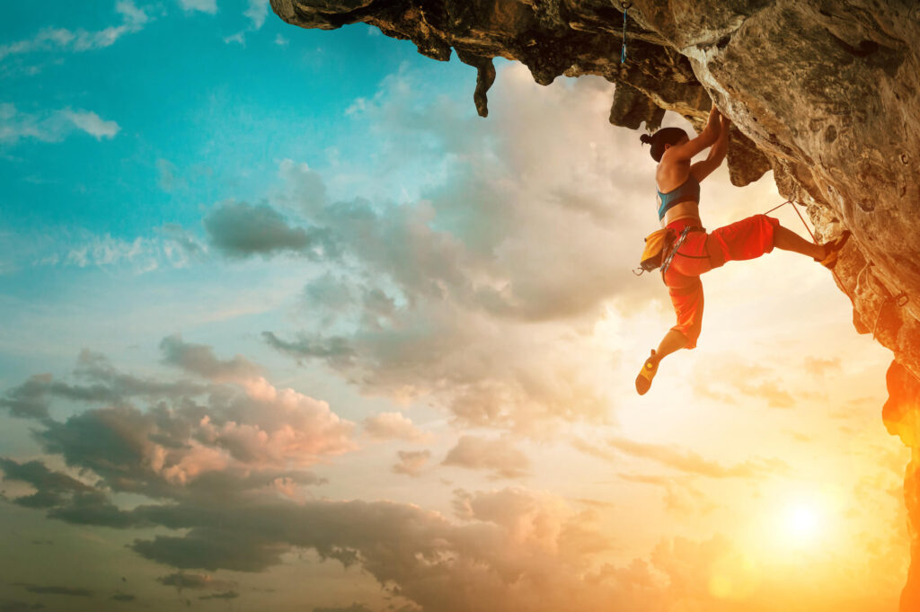 A woman climbs a steep mountain and is secured with ropes