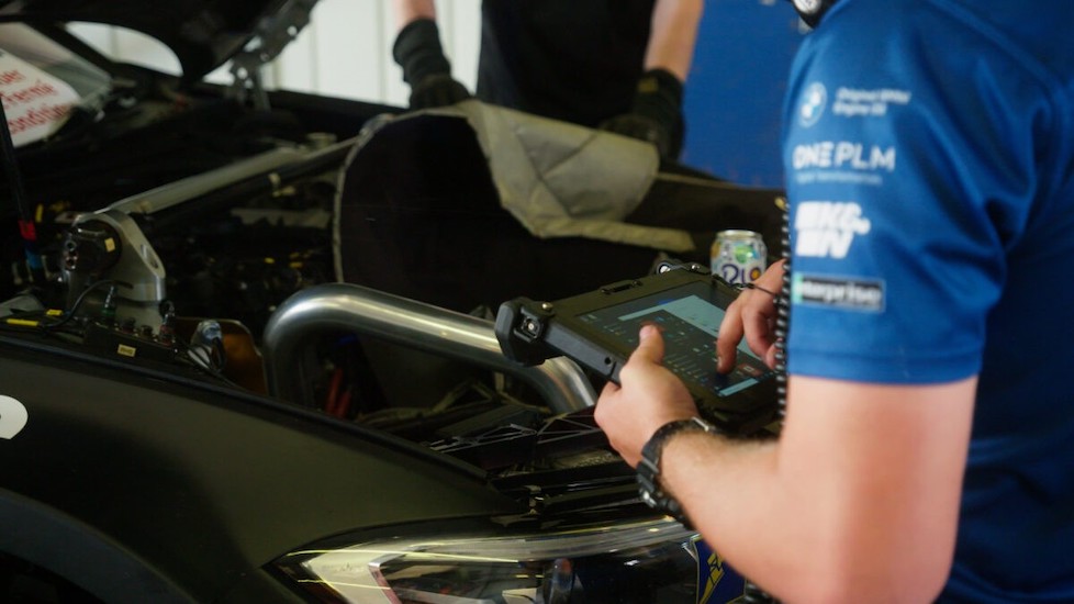 A man checks the settings on a diagnostic computer connected to the car