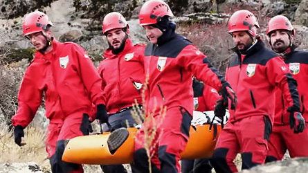 A group of paramedics is carrying a stretcher down the mountain